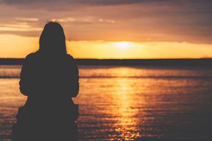 Silhouette of a woman watching the sunset over the water