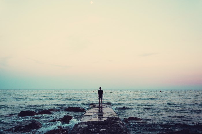 Man standing on a pier looking at the ocean