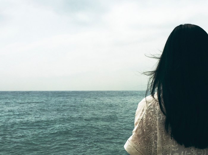 Woman with black hair looking out at the sea