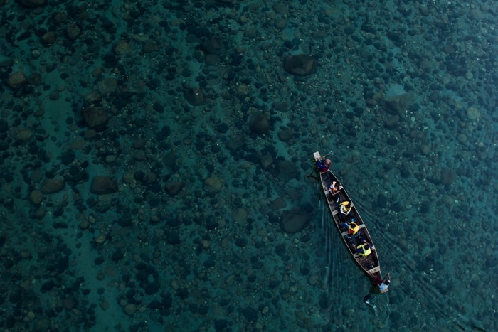 People rowing a boat on a clear river in Meghalaya