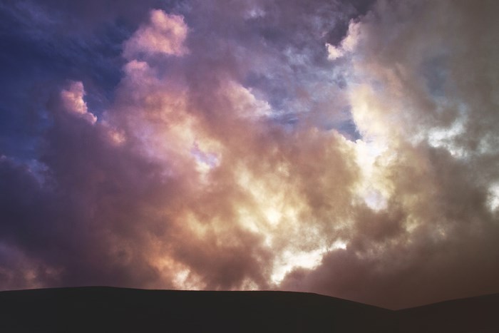 Dramatic clouds at sunset over a silhouetted hill
