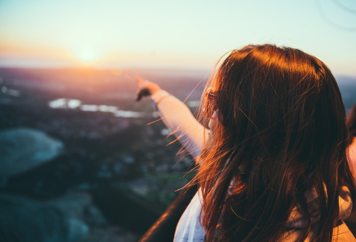 Woman pointing at the sunset over a landscape