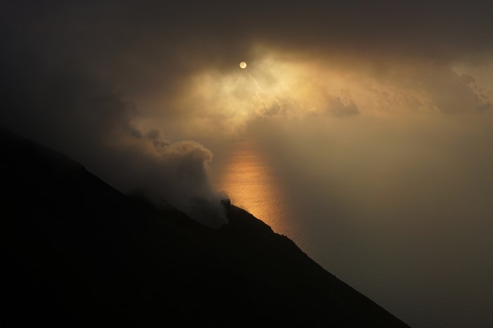 Sunset over the sea with clouds and volcano smoke