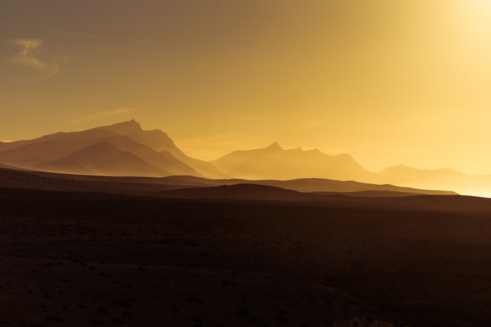 Mountain range silhouetted against a golden sunset sky