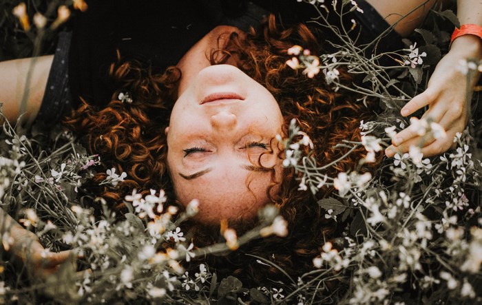 Redhead woman resting among flowers