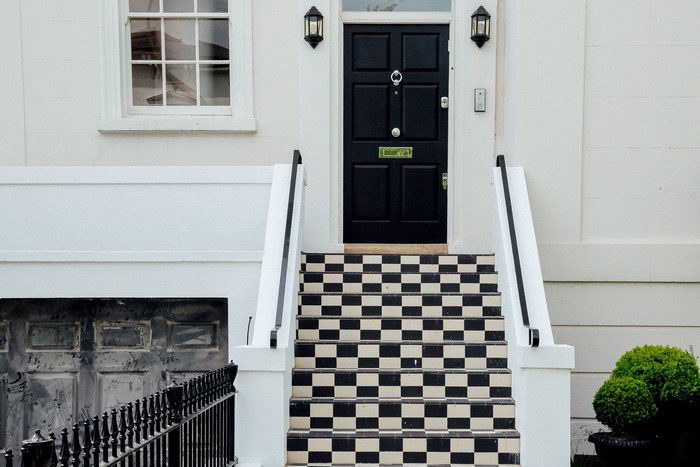 Black front door with checkered stairs and white railing