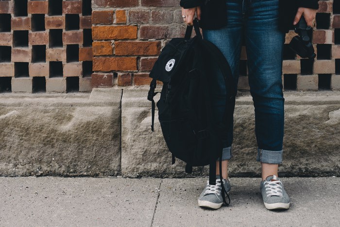 Person holding a black backpack and camera