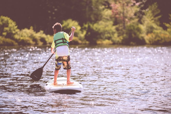 Boy on a paddleboard with a paddle and life jacket