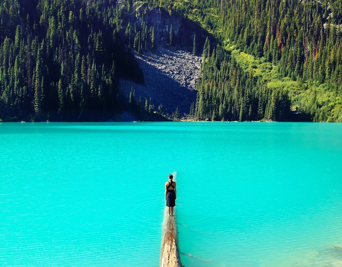 Woman standing on a log in Joffre Lake, British Columbia