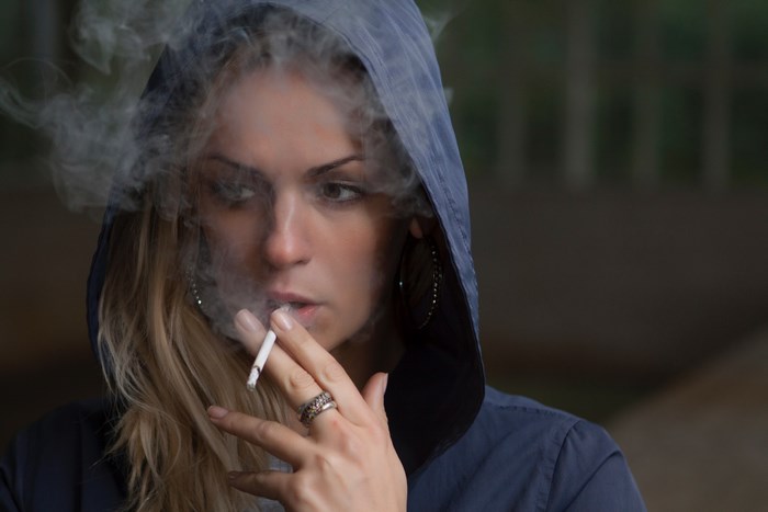 Woman in hoodie smoking a cigarette