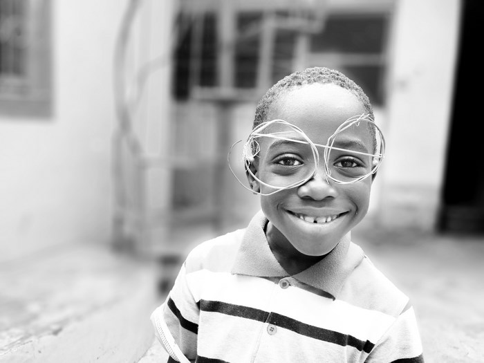 African boy wearing wire glasses and smiling