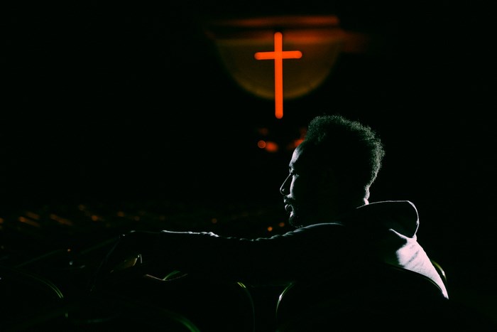 Man in front of a glowing orange cross