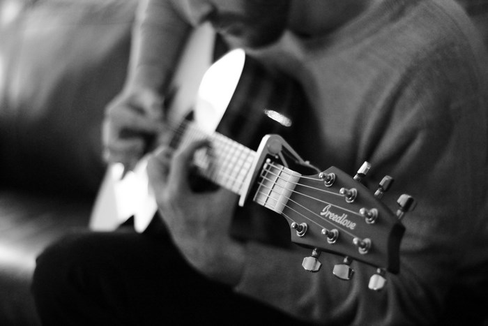 Man playing a Breedlove guitar with a capo