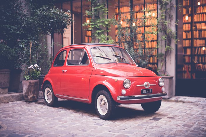 Red Fiat 500 parked in front of a library