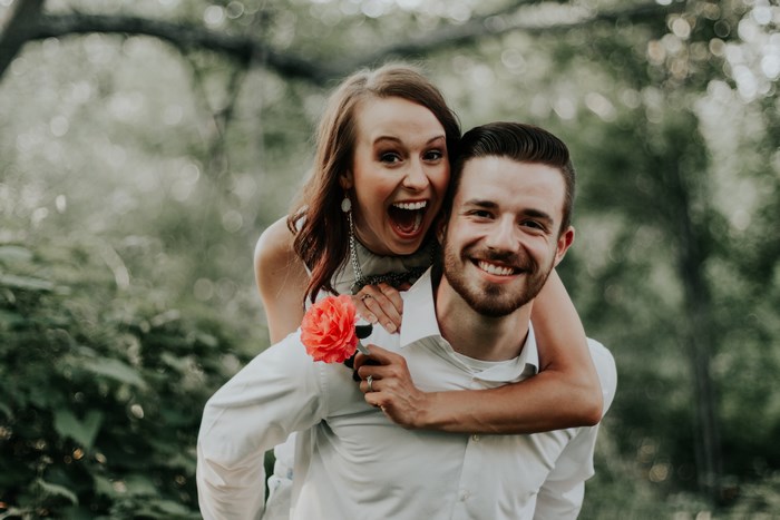 Couple with flower on piggyback ride outdoors