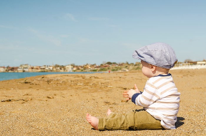 Boy Sitting on Sandy Seaside Beach in Summer