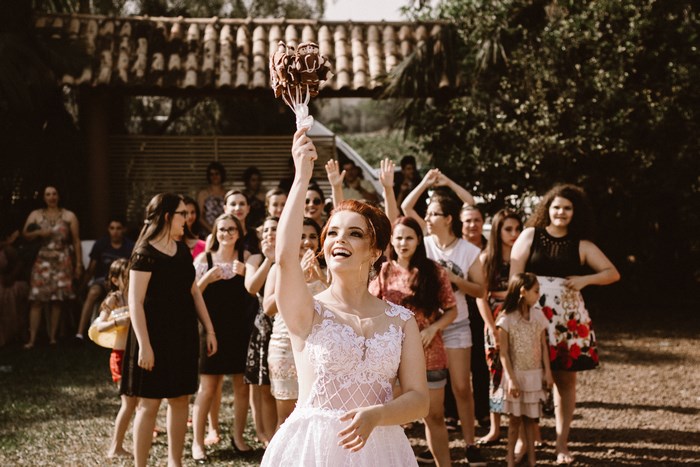 Bride throwing bouquet at outdoor wedding