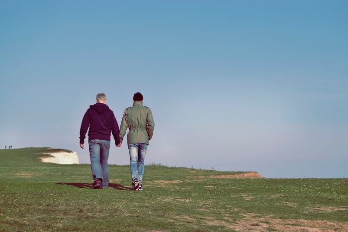 Couple holding hands walking on a cliff
