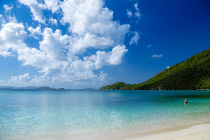 Person swimming in clear turquoise water near a tropical island