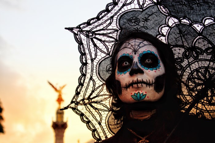 Woman with Dia de los Muertos face paint and umbrella