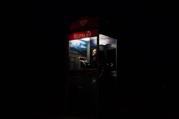 Person in a Telstra Air phone booth at night