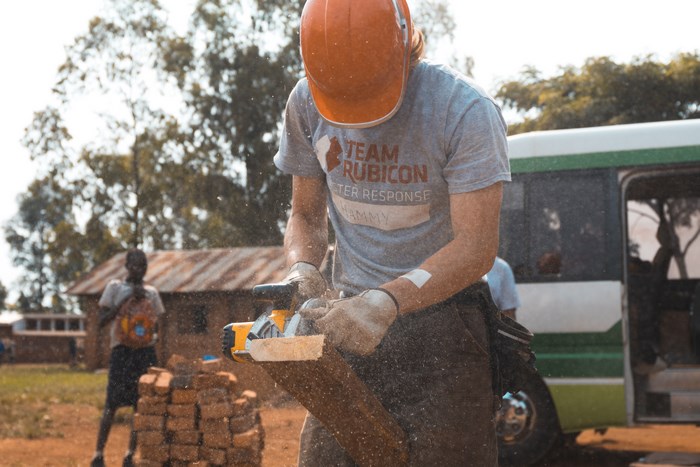 Team Rubicon worker cuts wood with a power saw
