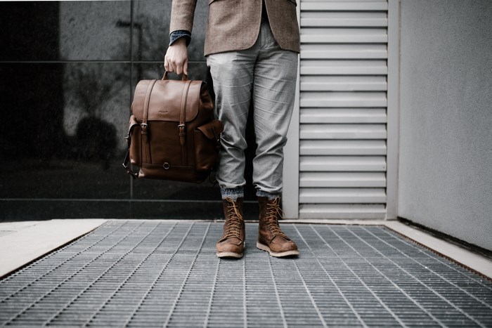 Man in tweed jacket carrying a brown leather backpack