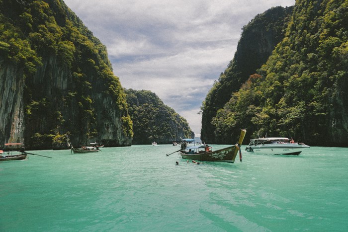 Boats in a turquoise bay surrounded by lush green cliffs