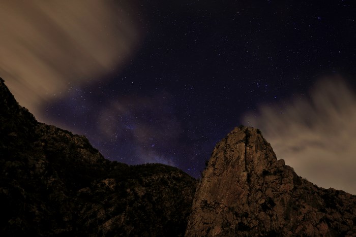 Night sky over rocky mountains with clouds