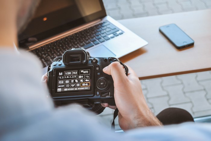 Canon DSLR camera settings on a table with laptop and phone
