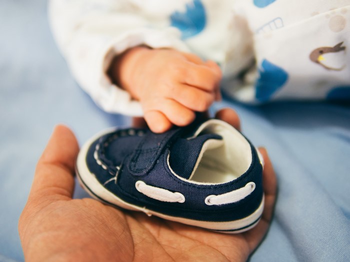 Baby's blue shoe held by a hand