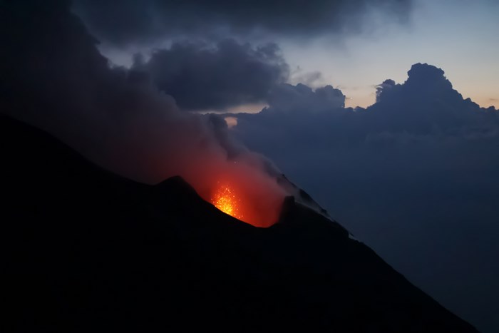 Volcano eruption with lava and smoke at dusk