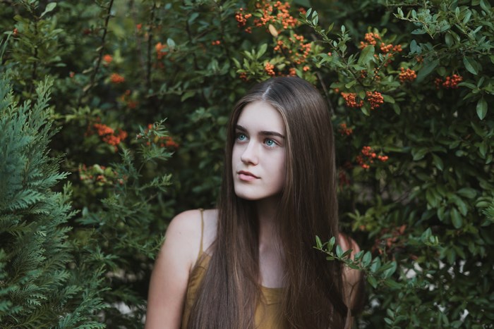 Young woman with long brown hair in foliage