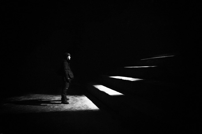Person standing in dark with illuminated stairs