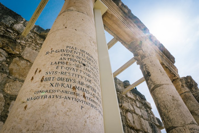 Ancient stone pillar with Latin inscription in ruins