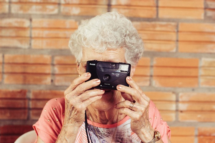 Elderly woman taking a photo with a Kodak camera