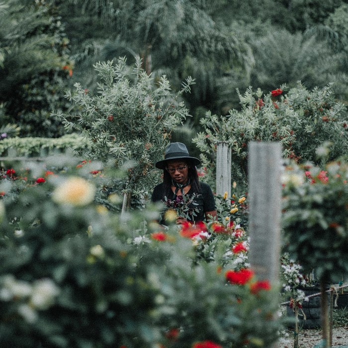 Woman in Hat Holding Flowers in a Garden