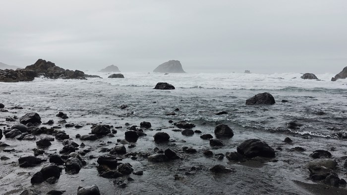 Rocky coastline with waves under a foggy sky