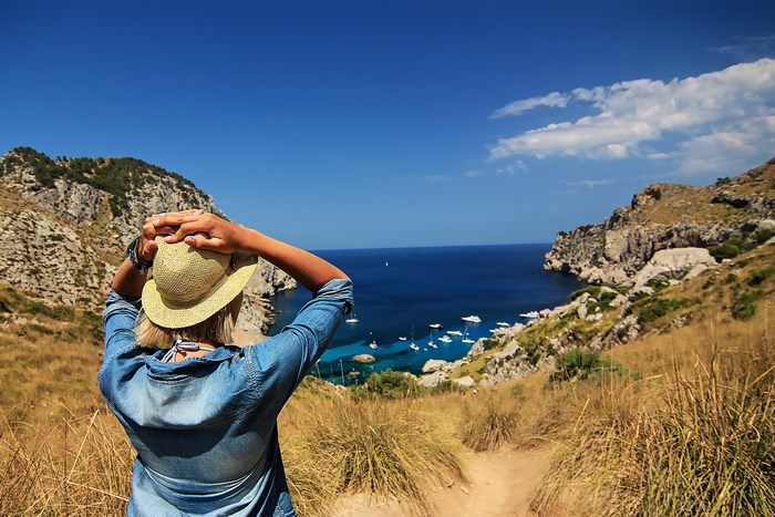 Woman in straw hat overlooking a bay with boats