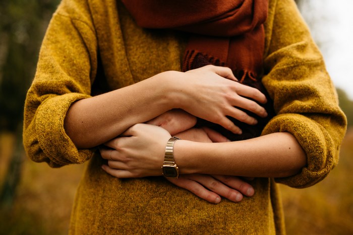 Couple hugging in autumn with yellow sweater and orange scarf