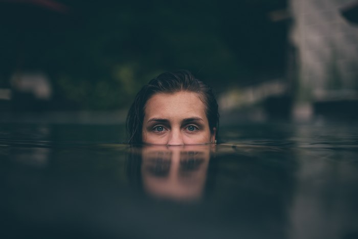Woman's eyes emerge from dark water
