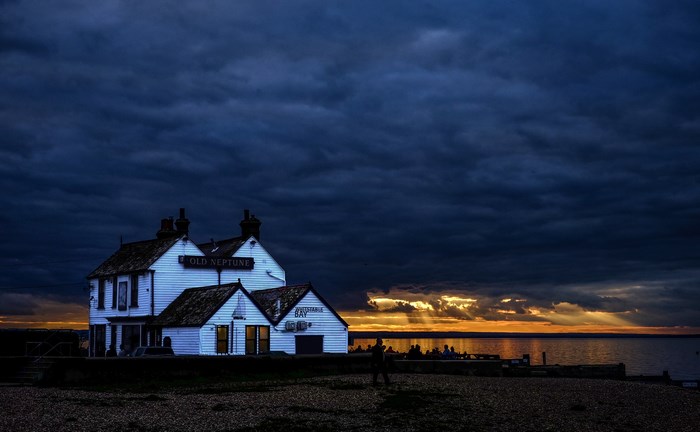 Old Neptune building at sunset with dark clouds