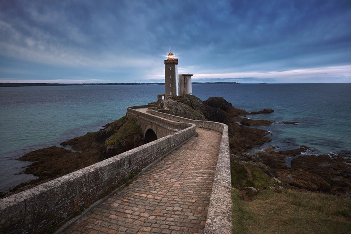 Lighthouse on a rocky island with a stone bridge