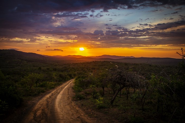 Dirt road through African landscape at sunset