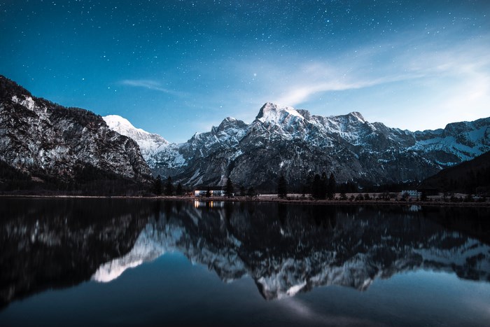 Snowy mountains reflected in a lake under the stars