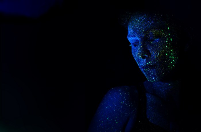 Woman with glowing blue and green paint on face