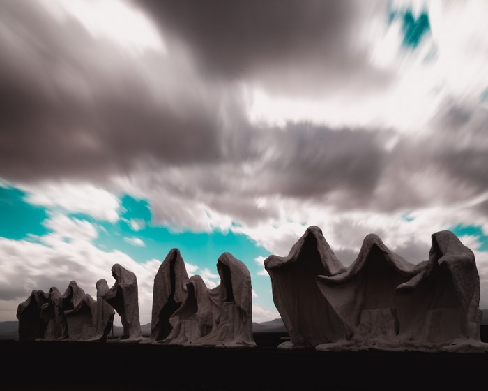 Sculptures in a desert landscape under a cloudy sky