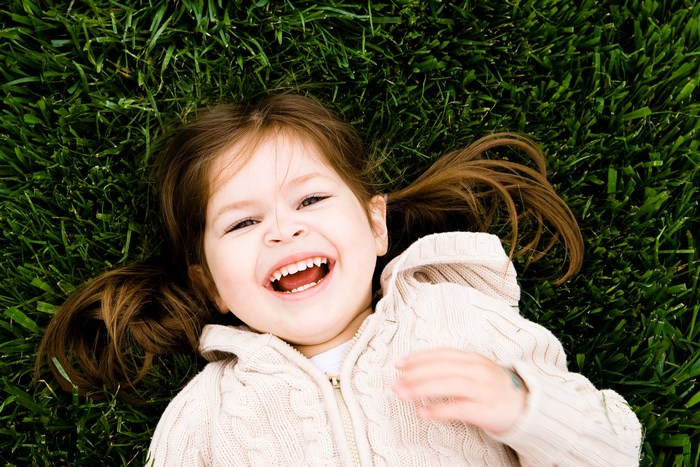 Happy toddler girl lying on grass