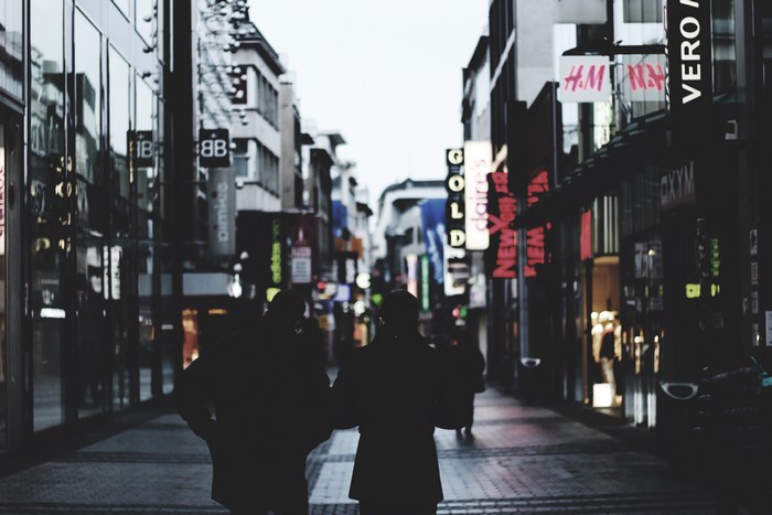 Couple walking on a street with shops at night