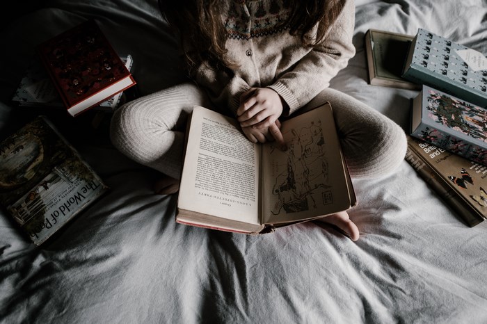 Child reading books on a bed
